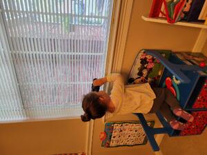 Image of a girl looking out a window with binoculars