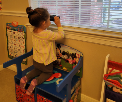 Image of a girl looking out a window with binoculars